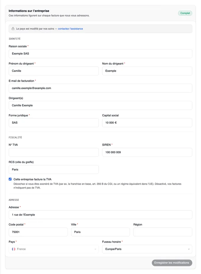 La carte « Informations sur l’entreprise » marquée « Complet », sous le titre l’avis « Le pays est modifié par nos soins — contactez l’assistance », les sections Identité, Fiscalité et Adresse remplies avec les données d’exemple d’Exemple SAS — SAS, capital social 10 000 €, SIREN 100 000 009, RCS Paris, le pays France grisé —, et le bouton « Enregistrer les modifications » en bas.
